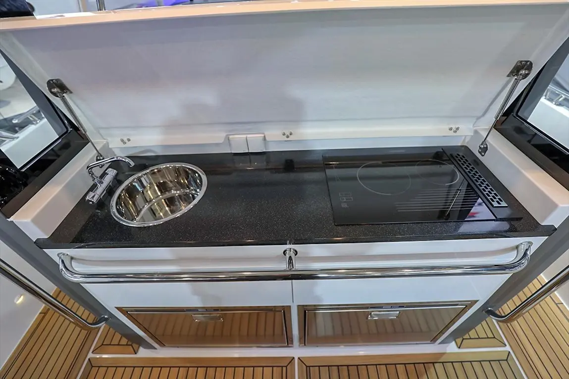 Compact marine kitchen with stainless steel sink, induction cooktop, and sleek cabinetry, ideal for boat cooking.